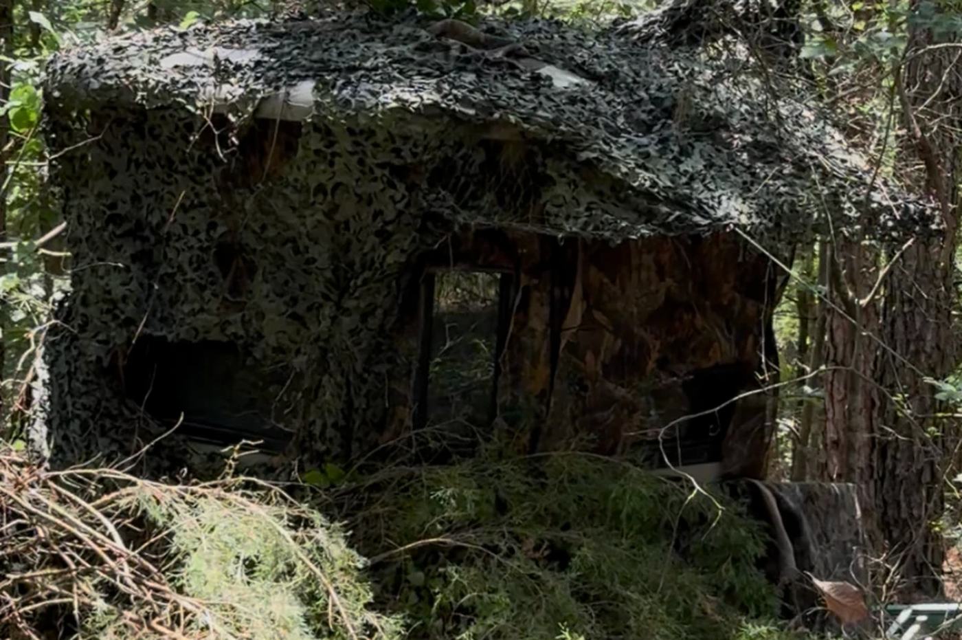 A box blind wrapped in camo netting, tucked into the timber