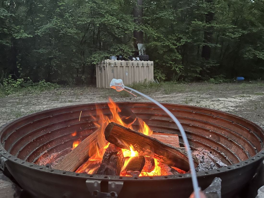 A campfire burning in a steel fire ring at dusk