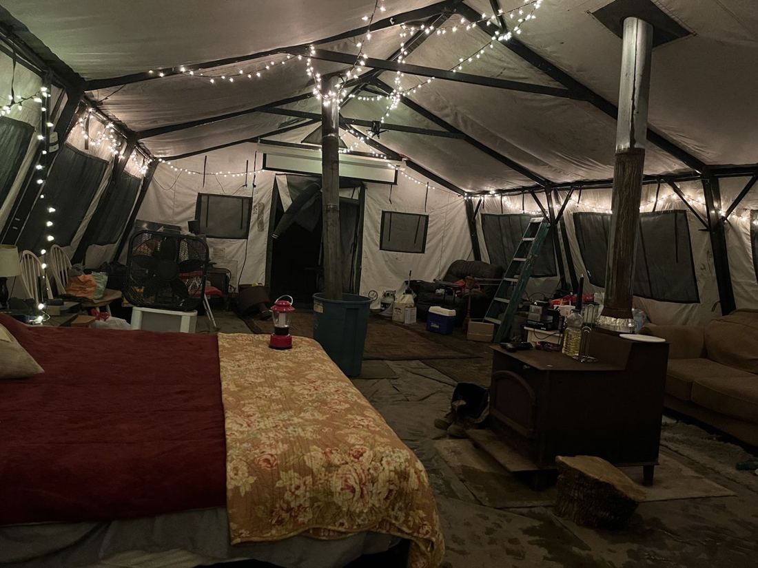 Inside a big canvas camp tent lit with string lights